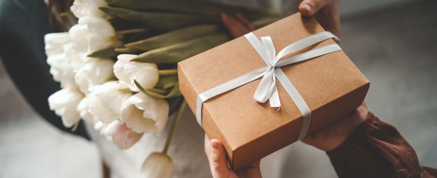 young girl handing over mothers day gifts including flowers